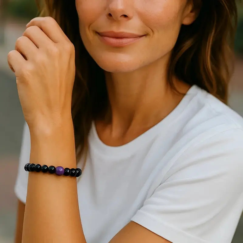 Woman wearing a white t-shirt and black beaded bracelet, with a blurred background