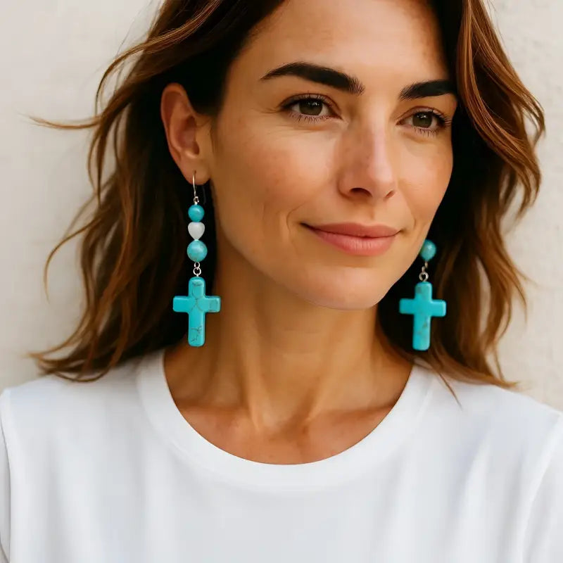 Woman wearing stunning turquoise earrings with cross and heart shape design