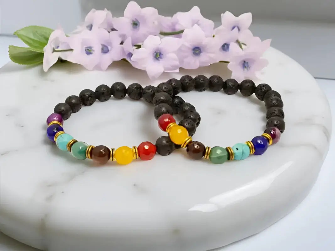 Two beaded chakra bracelets featuring black lava stone diffuser and essential oils